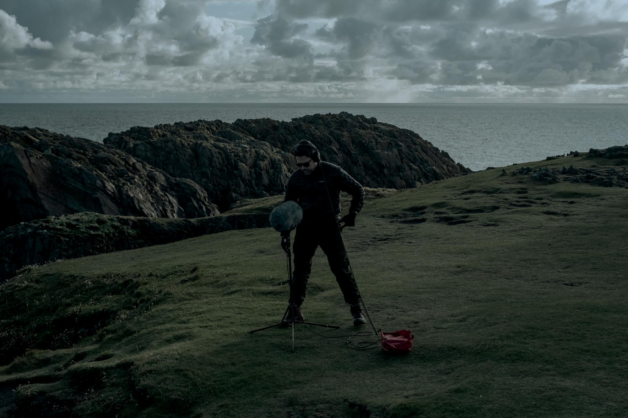 Rodrigo Rubilar on a Scottish cliff, recording with a field microphone